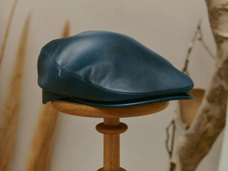 Marineblaue Flat Cap aus Wachsbaumwolle auf einem Holzständer